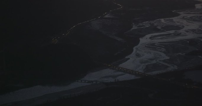 Aerial helicopter wide shot, slow push in on highway over frozen river at night time, drone footage