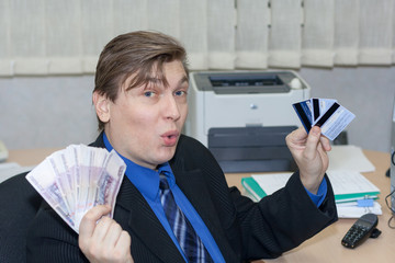 the cheerful manager holds several credit cards and a wad of money