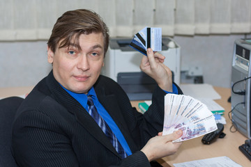 the cheerful manager holds several credit cards and a wad of money