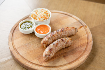 Grilled sausages. Serving on a wooden Board. Barbecue restaurant menu, a series of photos of different meats. Pickled cabbage and two sauces