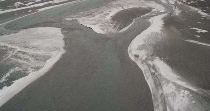 Aerial helicopter shot, circling around and zooming in on a bald eagle tearing into the fresh salmon in his talons with his beak, camera pulls out to show the vastness of the river valley, drone footage