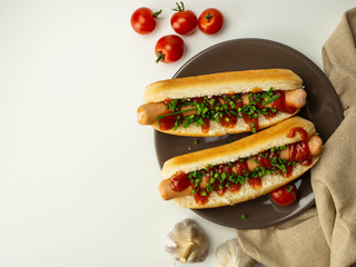 Hot dog przygotowany w domu, parówka, szczypiorek, bułka, pomidor. Widok z góry.