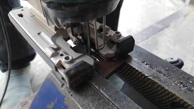 Worker cutting steel. Cutting metal workpiece using jigsaw in home workshop, slow motion