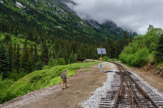 Train railways in Skagway, Alaska. Man is working on a station. He is going to the solar panel. It is very fogy.