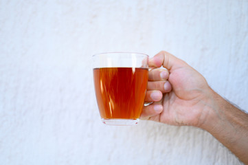 glass cup of tea in the male hand