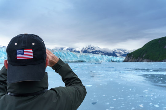 Man in hat with USA flag is taking a photo of a Hubbard Glacier. He is on a cruise in Alaska. Expedition to the glaciers