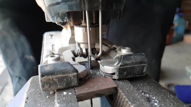 Cutting metal workpiece using jigsaw in home workshop, slow motion