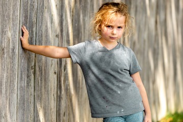 Young girl leaning against wooden fence