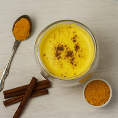 Turmeric milk with spice on a white wooden background. Healthy drink. Top view