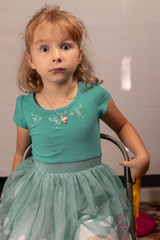 Young girl in teal dress looking surprised