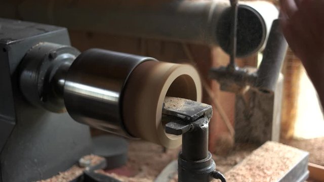 Craftsman working with wood carving machine. Flying sawdust in workshop. Worker using carpentry equipment. Woodworking industry.