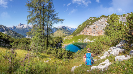 Beautiful mountain landscape with lake and female hiker in summer