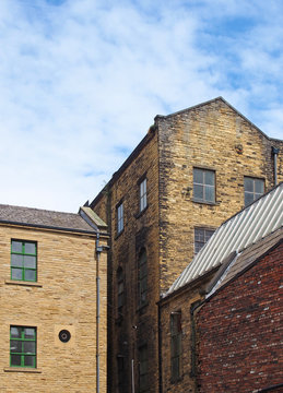 old 19th century stone warehouse and factory buildings in bradford west yorkshire against a blue cloudy sky