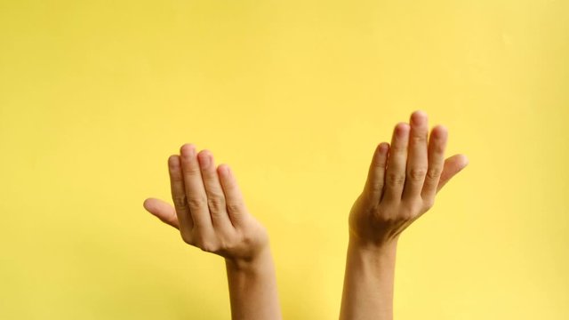 Closeup of female hands making gesture Come closer on the background yellow paper. Body language concept. With place for text or image, promotional content. Advertising area, workspace mock up