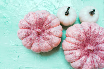 Pink and white pumpkins with glitter on neo mint background, creative concept. Festive advertising...