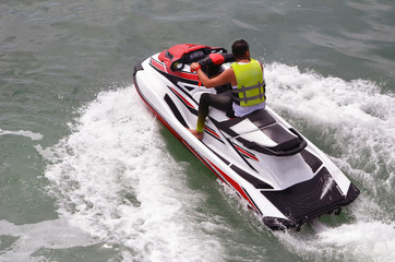 Angled overhead view of a man riding a speeding red and white jetski