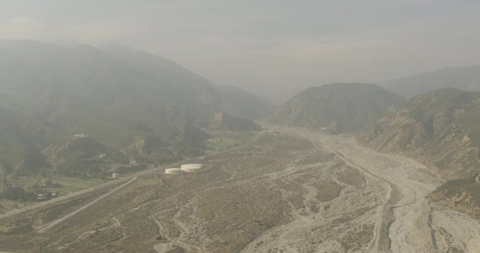 Aerial shot, day, hazy view of mountain range and river deposit, drone