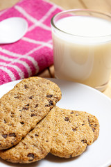 FIRST FLAT OF COOKIES WITH CHOCOLATE CHIPS AND MILK GLASS ON KITCHEN AND SPOON CLOTH. HEALTHY BREAKFAST