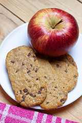 Naklejka na ściany i meble FIRST RED APPLE FLAT AND COOKIES WITH CHOCOLATE CHIPS ON WOOD BACKGROUND. HEALTHY BREAKFAST