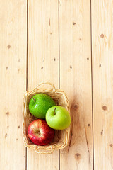 OP VIEW OF BASKET WITH VARIETY OF APPLES ON WOOD BACKGROUND. HEALTHY FOOD