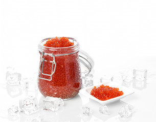 Salmon Keta red fish caviar in jar can and little plate with ice on table. Sea food