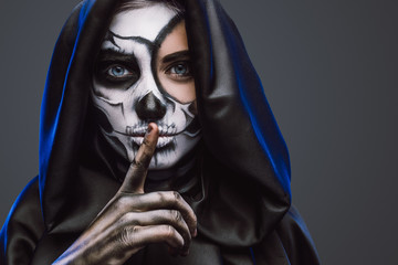 Female with spooky painted face and finger on lips
