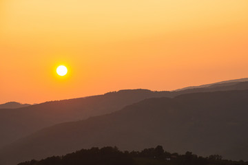 Orange sunset above serbian mountains with hills silhouette