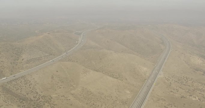 Aerial shot, day, hazy high altitude view of desert highway, drone