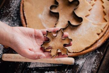 Christmas and New Year celebration traditions. Family home bakery, cooking traditional festive sweets. Woman cutting cookies of raw gingerbread dough