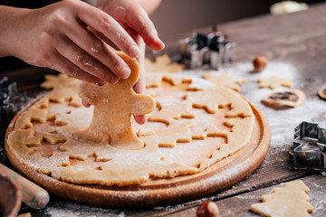 Christmas and New Year celebration traditions. Family home bakery, cooking traditional festive sweets. Woman cutting cookies of raw gingerbread dough