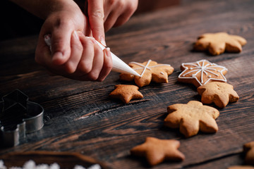 Christmas and New Year celebration traditions. Family cooking, traditional sweets. Decorating gingerbread cookie with confectionery icing, close up