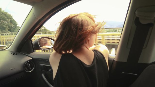 girl traveling by car enjoying the freedom and the breeze at her hair with the opened window