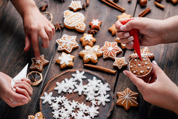 Christmas and New Year celebration traditions, festive sweets, family culinary. Traditional gingerbread. Friends decorating freshly baked cookies with icing and mastic - Powered by Adobe