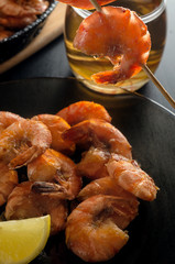 Fried shrimp with lemon on a platter, shrimp on a skewer and beer.