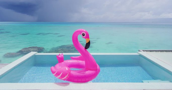 Pool Beach Vacation travel concept with inflatable pink flamingo float toy mattress in luxury swimming pool. Luxury lifestyle summer holidays travel background video.