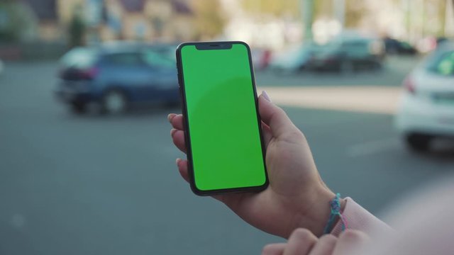 Young woman hands holding and touching phone with green screen vertically in the street internet technology touch business message mobile smart text networking outdoors slow motion