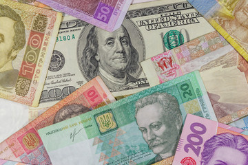 Fototapeta na wymiar One hundred dollar bill on a background of ukrainian hryvnia banknotes
