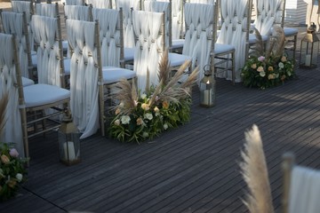 Shot of decorated white chairs for a wedding reception in the evening - obrazy, fototapety, plakaty