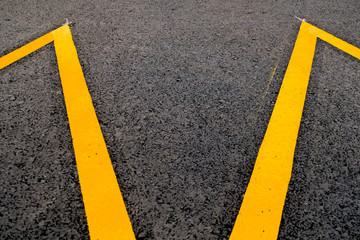 Band of yellow reflective paint on a black asphalt surface, an abstract perspective of road markings.