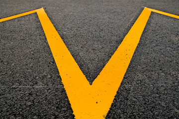 Band of yellow reflective paint on a tarmac pavement, an abstract detail in perspective.