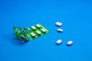 Medicine in green blister pack lying on a blue background.Health concept.