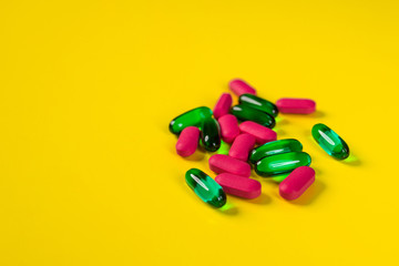 A small number of tablets and capsules on a yellow background.The concept of pharmacology.