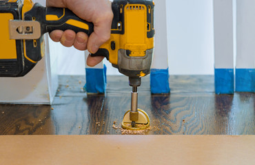 Metal modern professional installing door stopper on wooden floor.