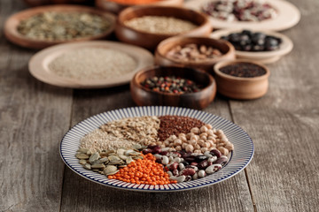 wooden and ceramic plates with legumes and cereals on brown table