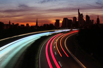Traffic with motion cars with luminous lines of speed and the evening European city of Frankfurt...