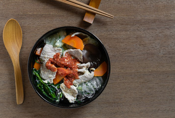 top view of pork sukiyaki in a ceramic bowl on wooden table. asian homemade style food concept.