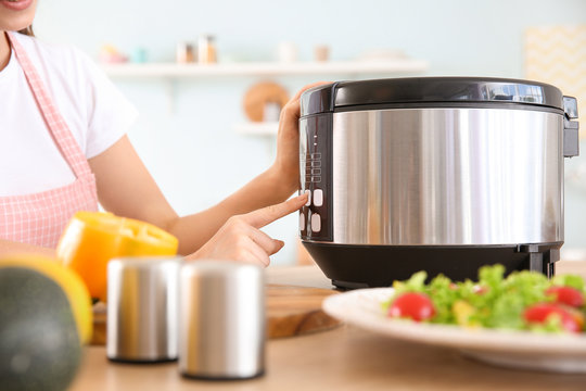 Woman using modern multi cooker in kitchen