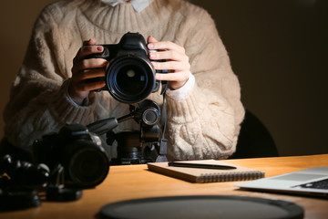 Female photographer working at table in evening, closeup