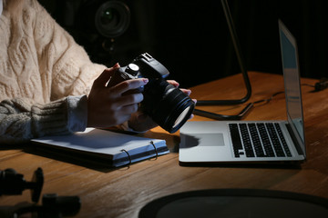 Female photographer working at table in evening, closeup