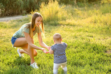 Fototapeta premium Mother teaching her little baby to walk outdoors